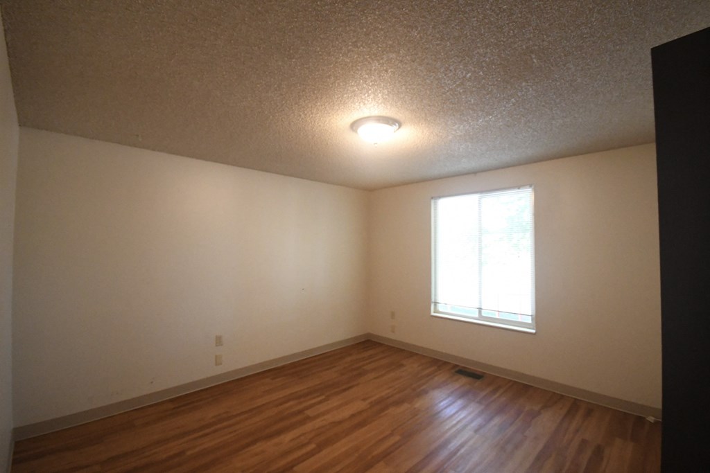 an empty living room with wood floors and a window