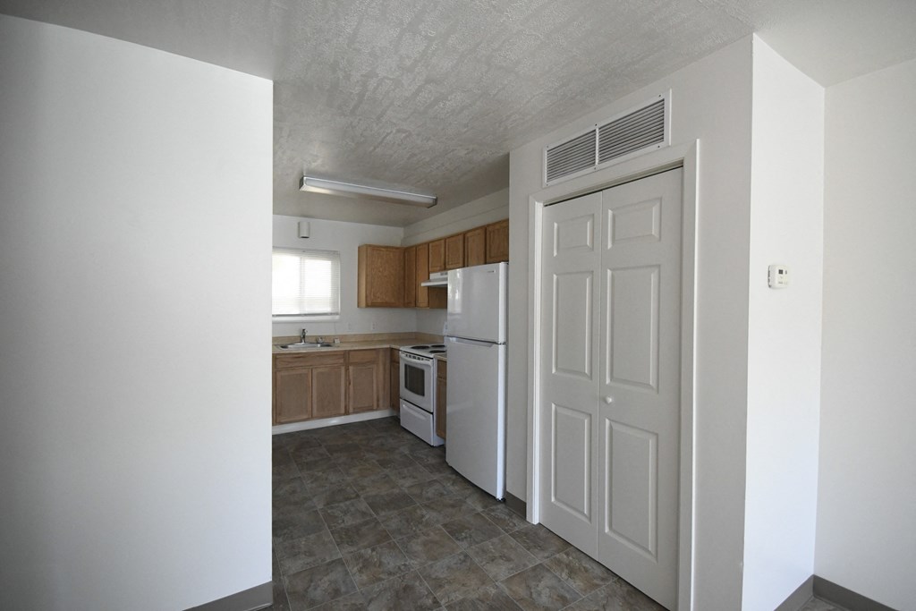an empty kitchen with white appliances and a white door
