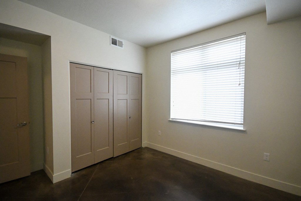 a bedroom with a window and a door and a closet