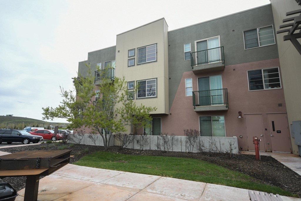 an exterior view of an apartment building with a yard and a sidewalk