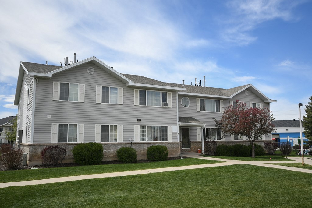 a gray house with a sidewalk in front of a green yard