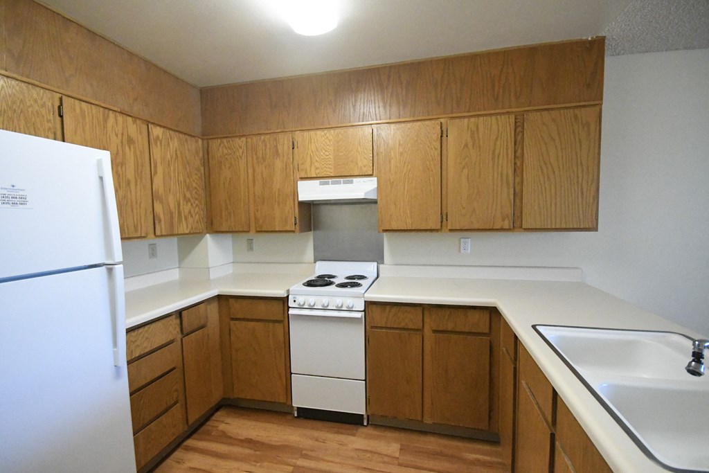 an empty kitchen with white appliances and wooden cabinets