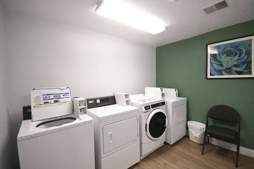 a laundry room with four washing machines and a chair