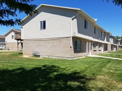 a white building with a green lawn and a blue sky