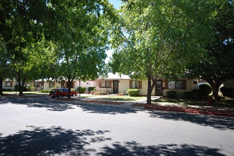 an empty street in front of an apartment complex with trees