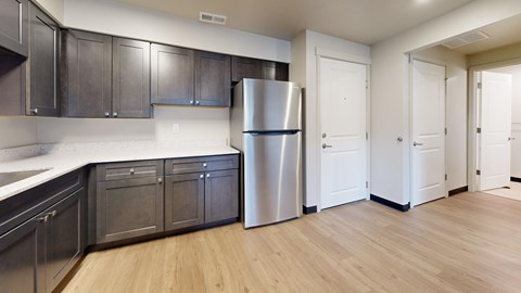 A kitchen with a refrigerator, cabinets, and a counter.