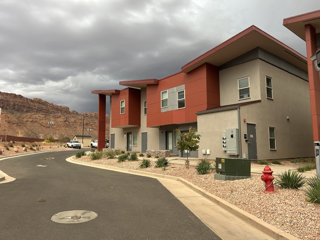 A red fire hydrant is on the sidewalk in front of a building.