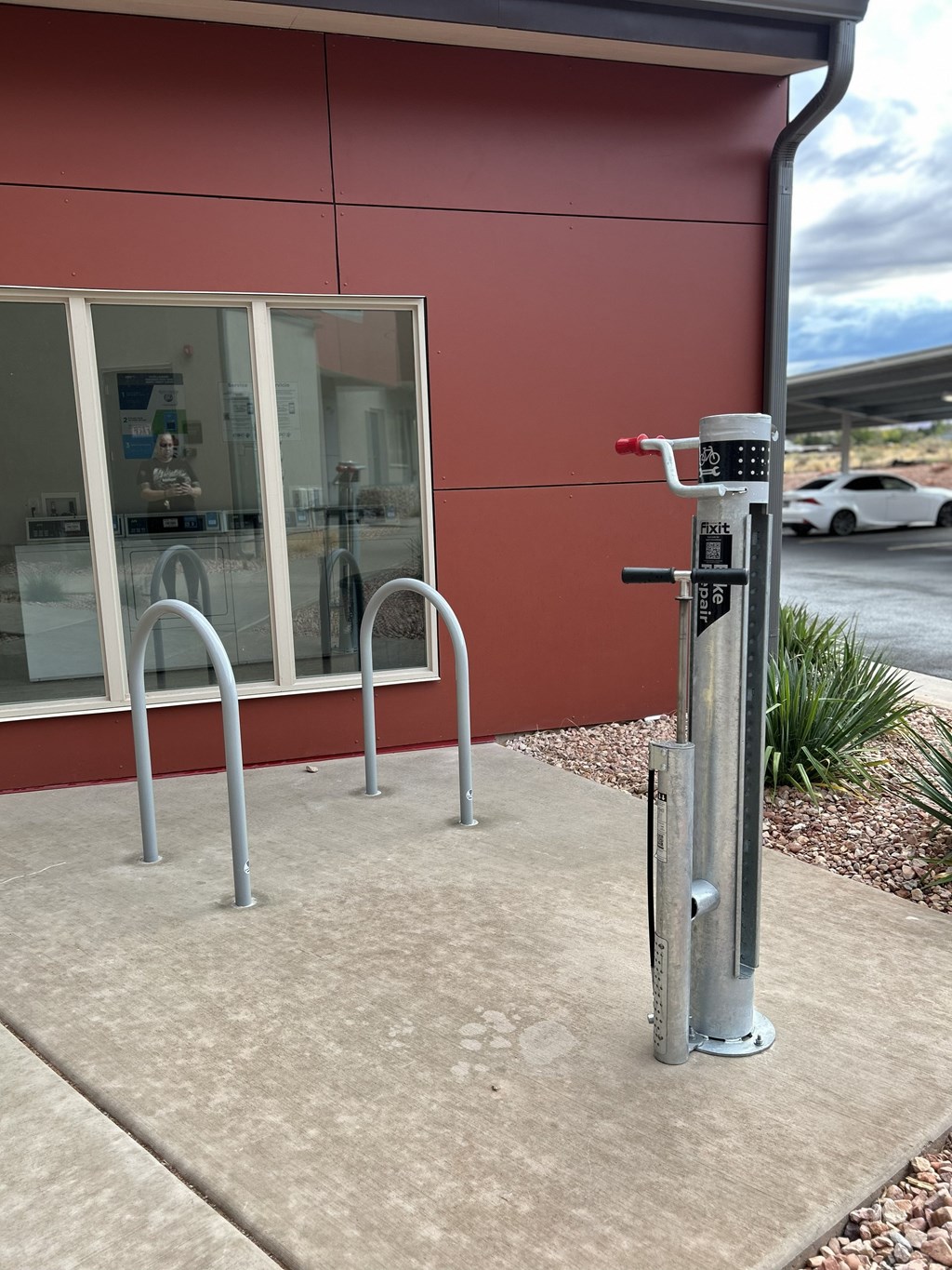 A parking meter is installed on a sidewalk in front of a building.