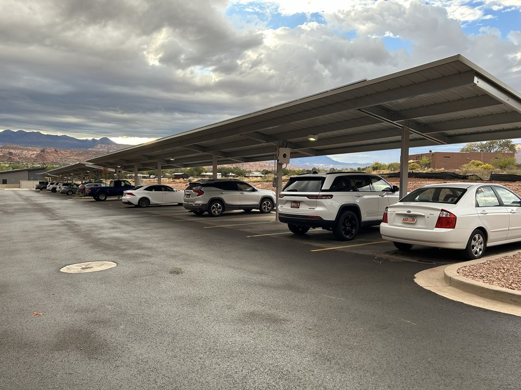 A parking lot with cars parked under a covered area.