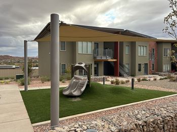A playground area in front of a modern apartment building.