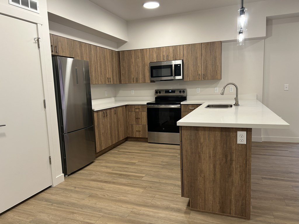 A kitchen with a refrigerator, oven, microwave, and sink.