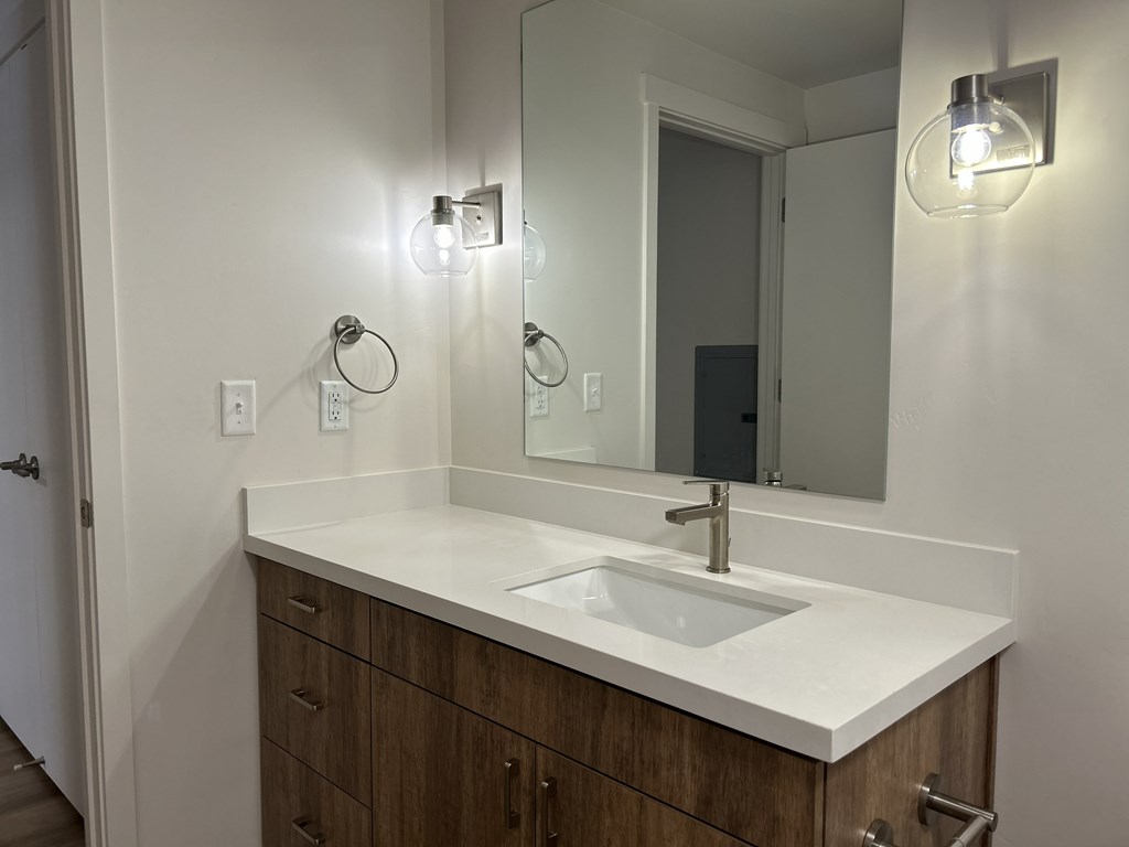 A bathroom with a sink, mirror, and lights.