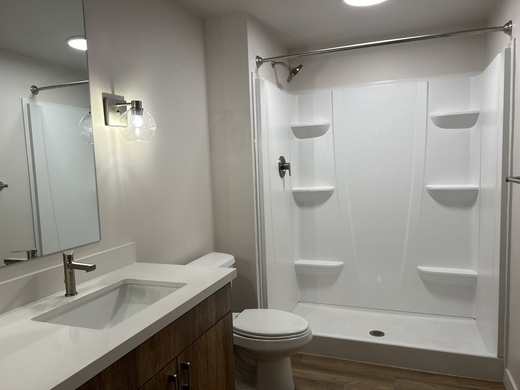 A white bathroom with a sink, toilet, and shower.