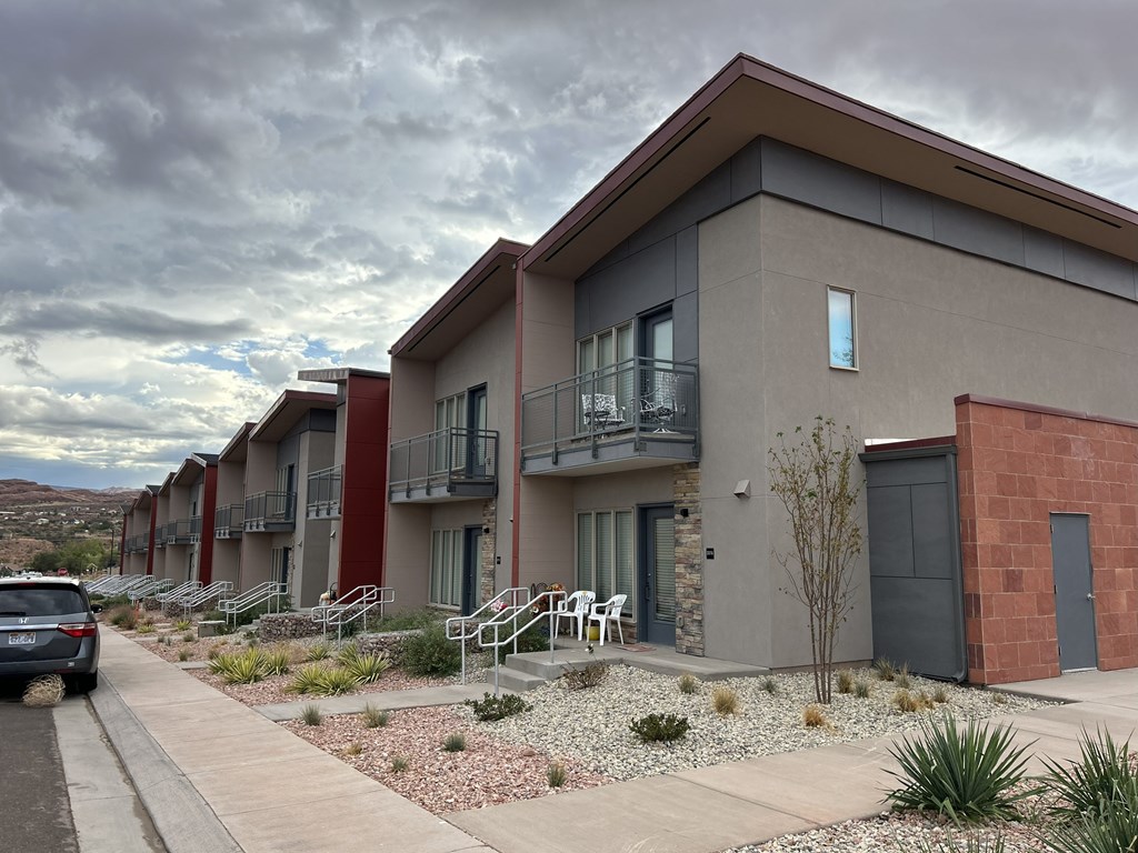 A row of modern townhouses with a car parked in front of the first one.