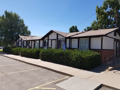 the front of a building with a parking lot and a sidewalk