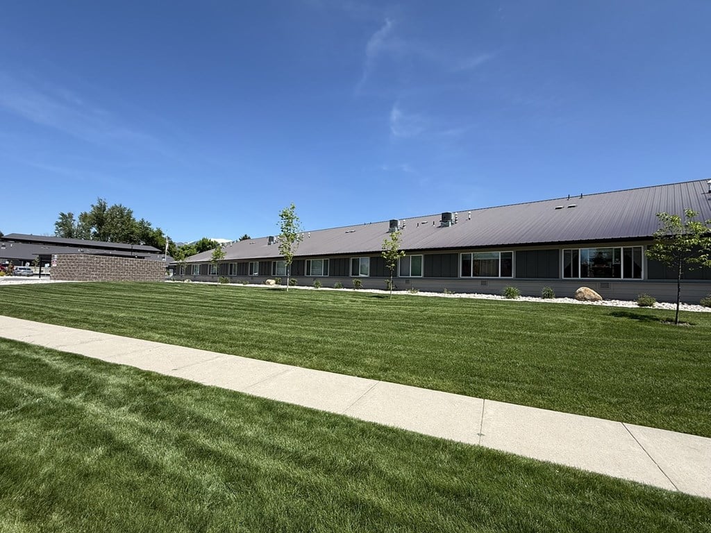A building with a grey roof and a green lawn in front.