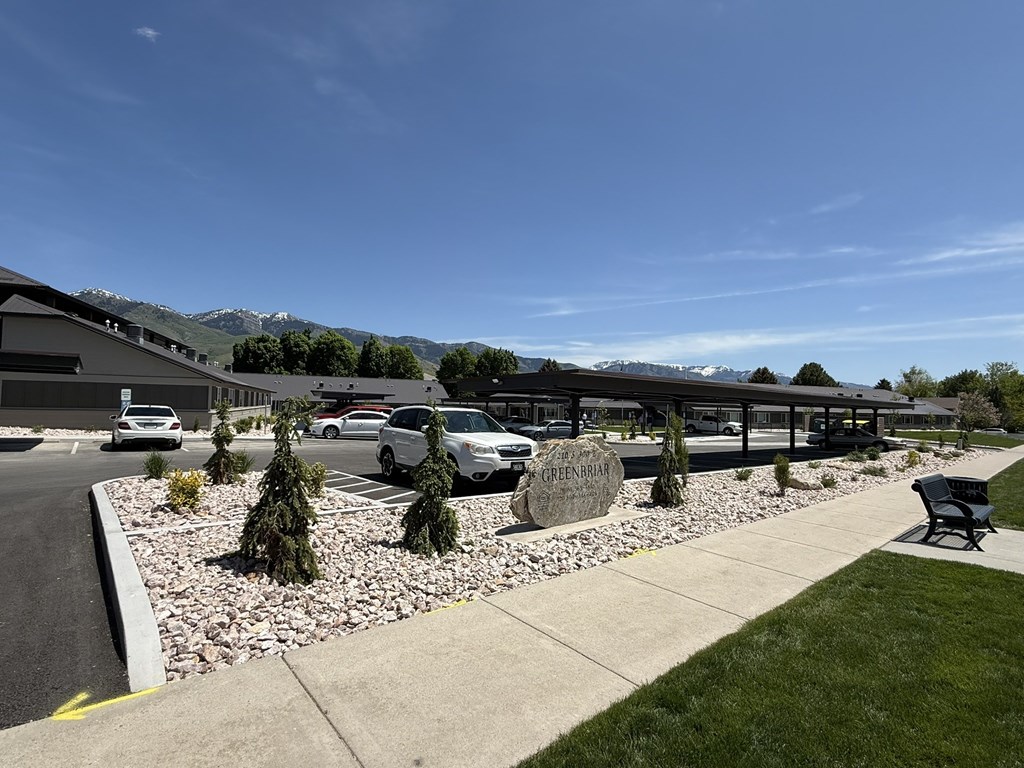 A parking lot with a sign that says "CHEERFUL" in front of a building with a mountain in the background.