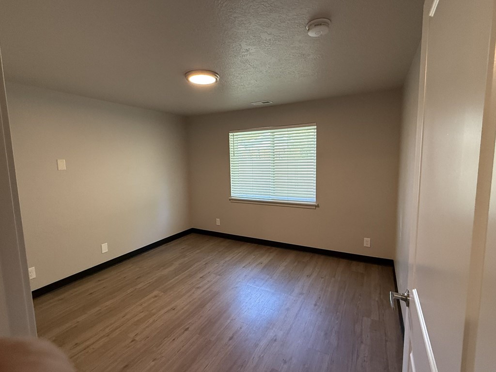 A room with wooden flooring and a window with blinds.