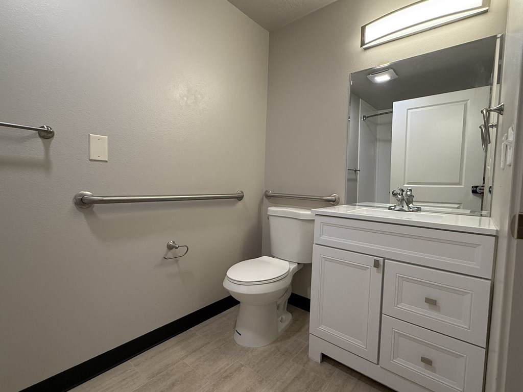 A white bathroom with a toilet, sink, and a mirror.