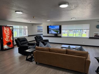 A living room with a couch, chairs, and a Coca-Cola machine.
