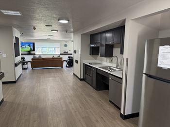 A kitchen with a refrigerator, sink, and cabinets.