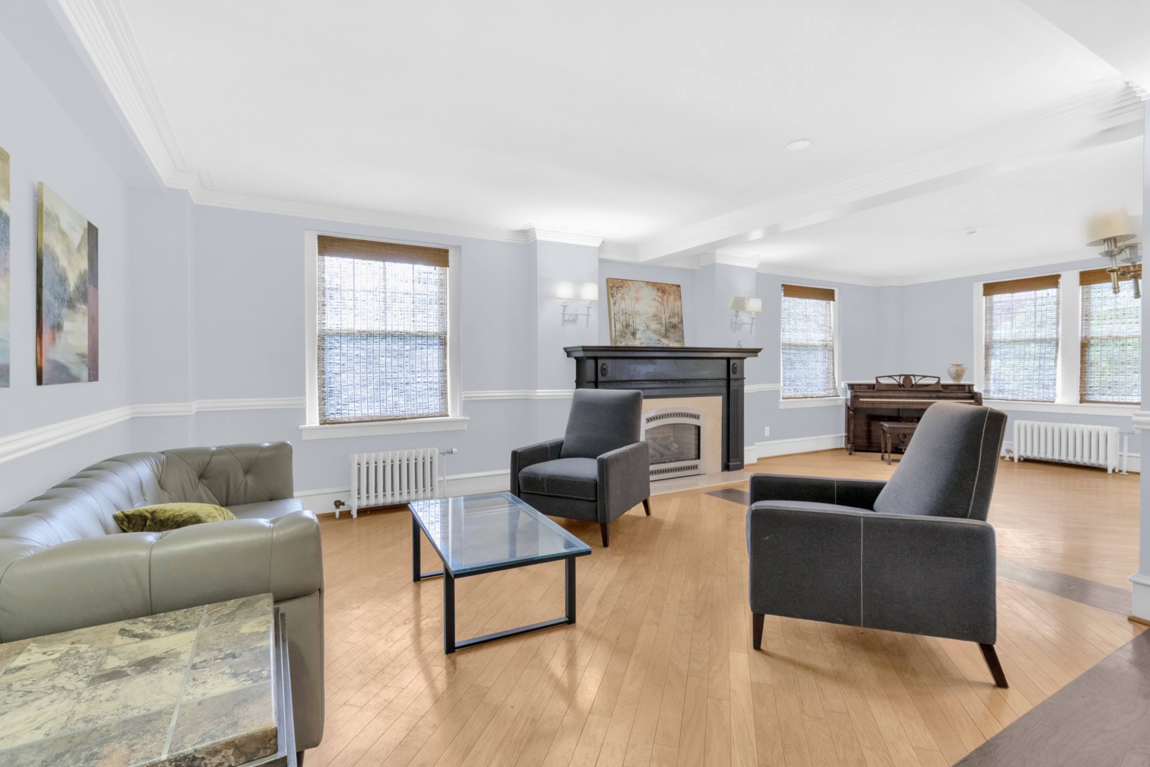 A living room with a fireplace and a grey couch.