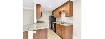A kitchen with a granite countertop and wooden cabinets.