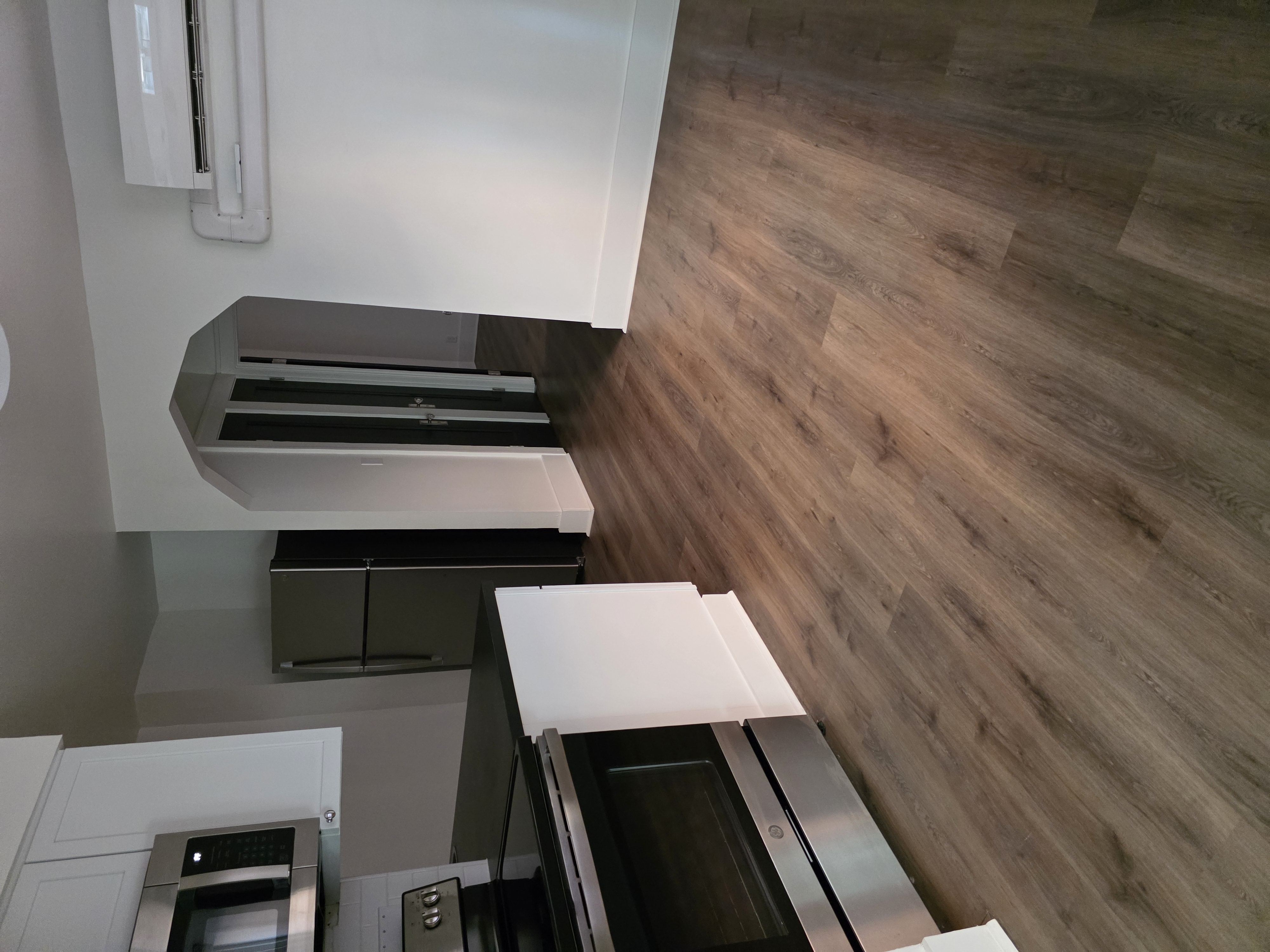 A modern kitchen with a stainless steel oven and a wooden floor.