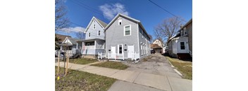 A grey house with a white fence in front of it.