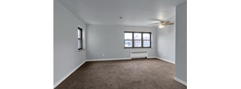 A room with a ceiling fan and a window with a view of a building outside.