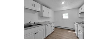 A kitchen with white cabinets and a window.