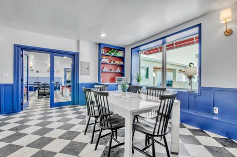 A dining room with a checkered floor and a white table.
