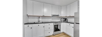 A kitchen with white cabinets and a black countertop.
