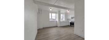 A spacious kitchen and living room with wooden flooring and white walls.