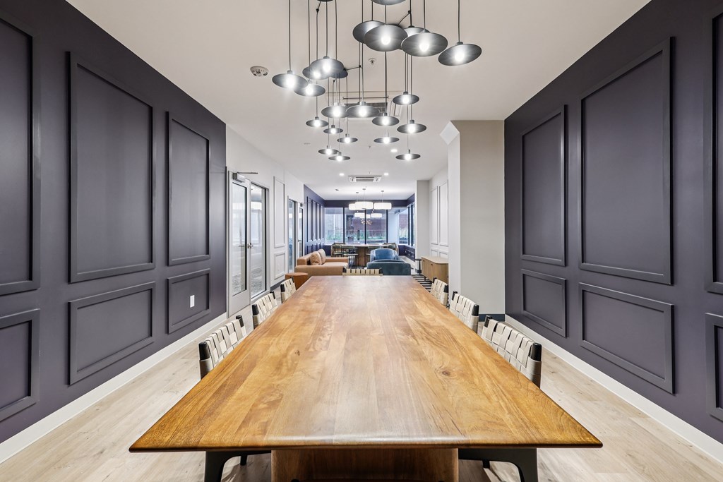 A long wooden table is surrounded by grey panels on the wall.