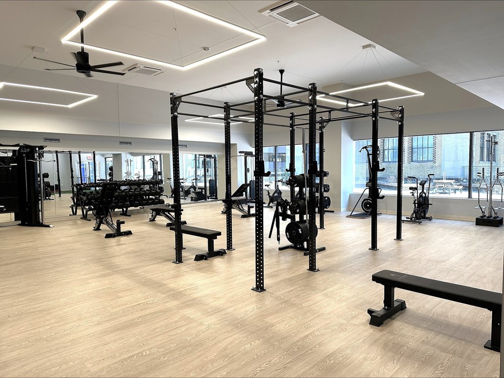 A gym with a variety of equipment including weightlifting machines and benches.