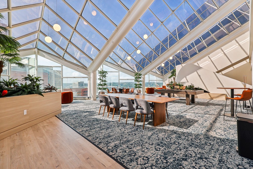 A modern dining area with a glass ceiling and wooden furniture.