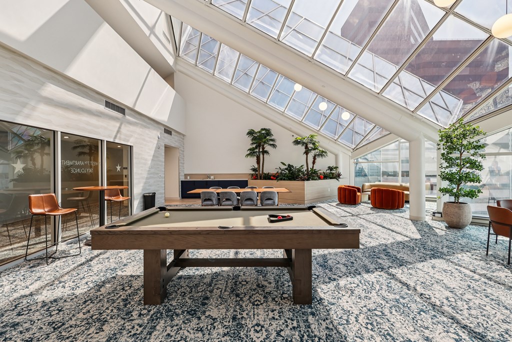 A billiard table is in the middle of a room with a glass ceiling.
