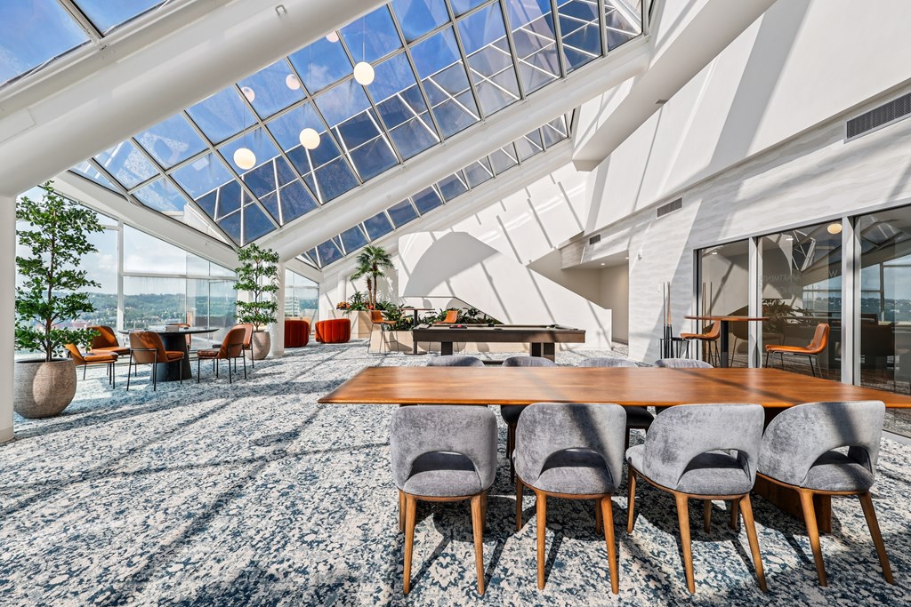 A modern dining room with a glass ceiling and a long wooden table.