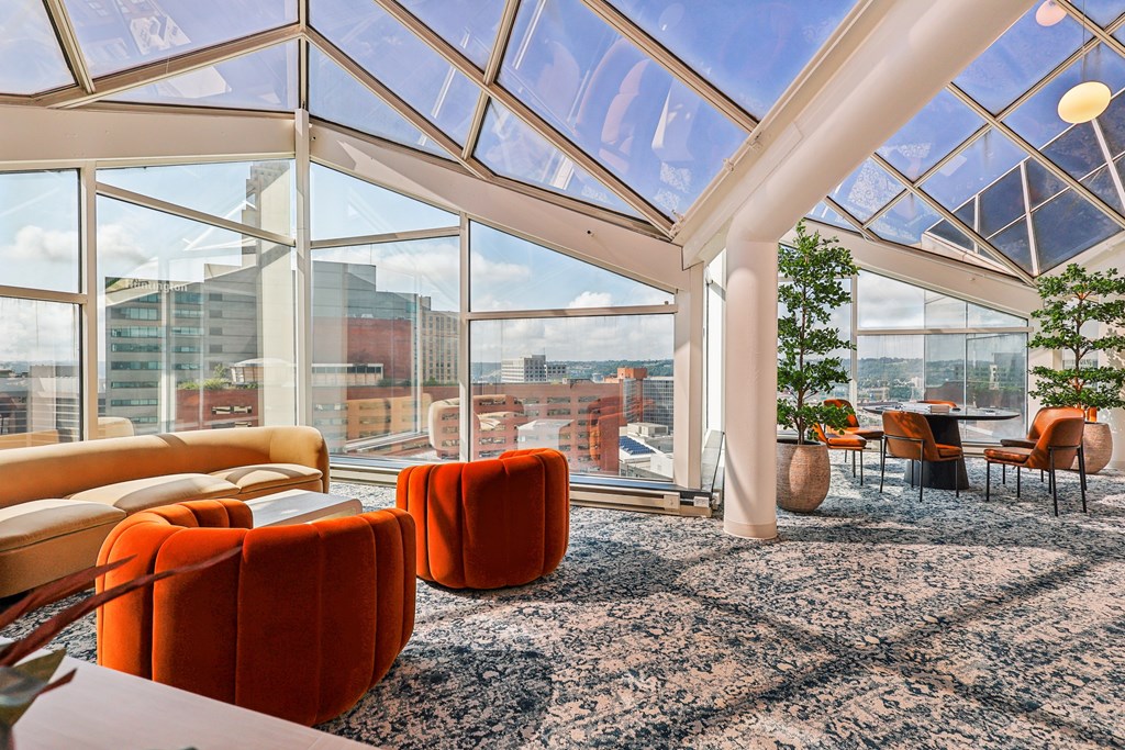 A room with orange chairs and a glass ceiling.