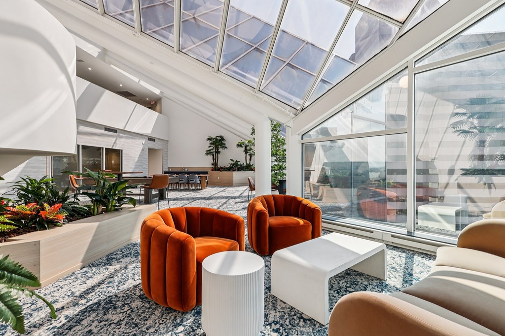 A modern living room with a glass ceiling and a variety of seating options.