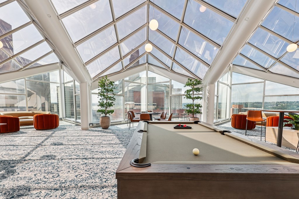 A billiard table is in the middle of a room with a glass ceiling.