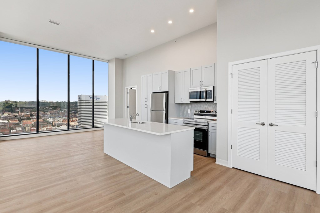 A kitchen with white cabinets and a large window overlooking a cityscape.