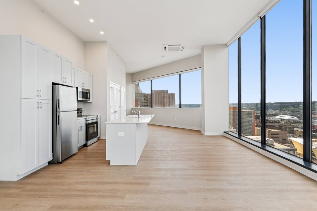 A modern kitchen with wooden floors and a large window overlooking the city.