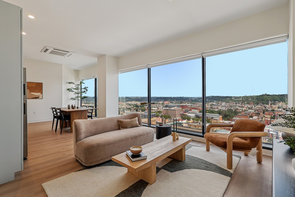 A living room with a couch, chair, and table with a view of the city.