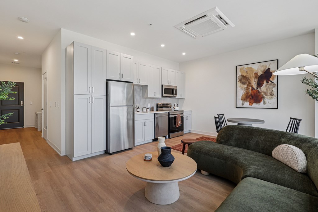 A modern kitchen with a green couch and a wooden table.