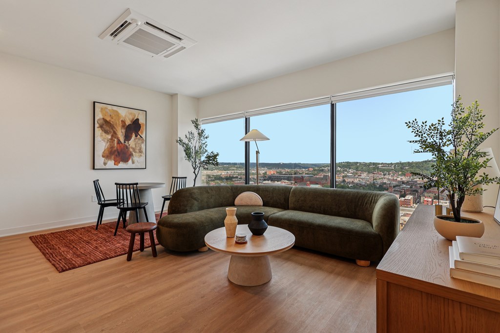 A living room with a green couch and a painting on the wall.