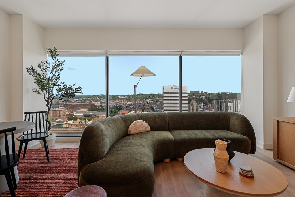 A living room with a green couch and a view of the city.