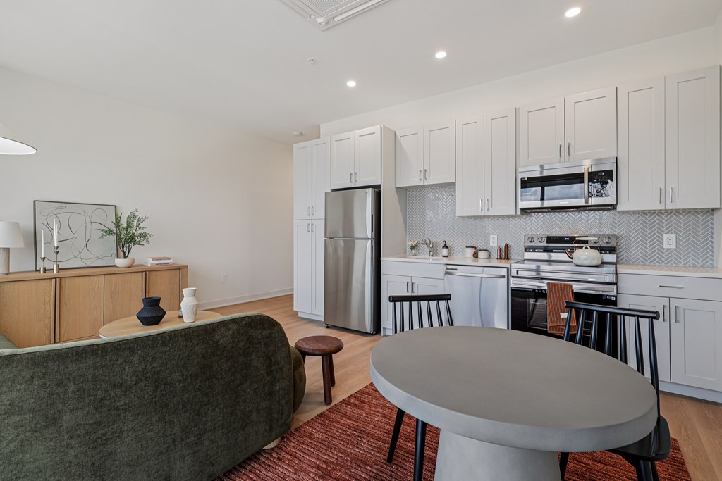A modern kitchen with a green couch and a grey table.