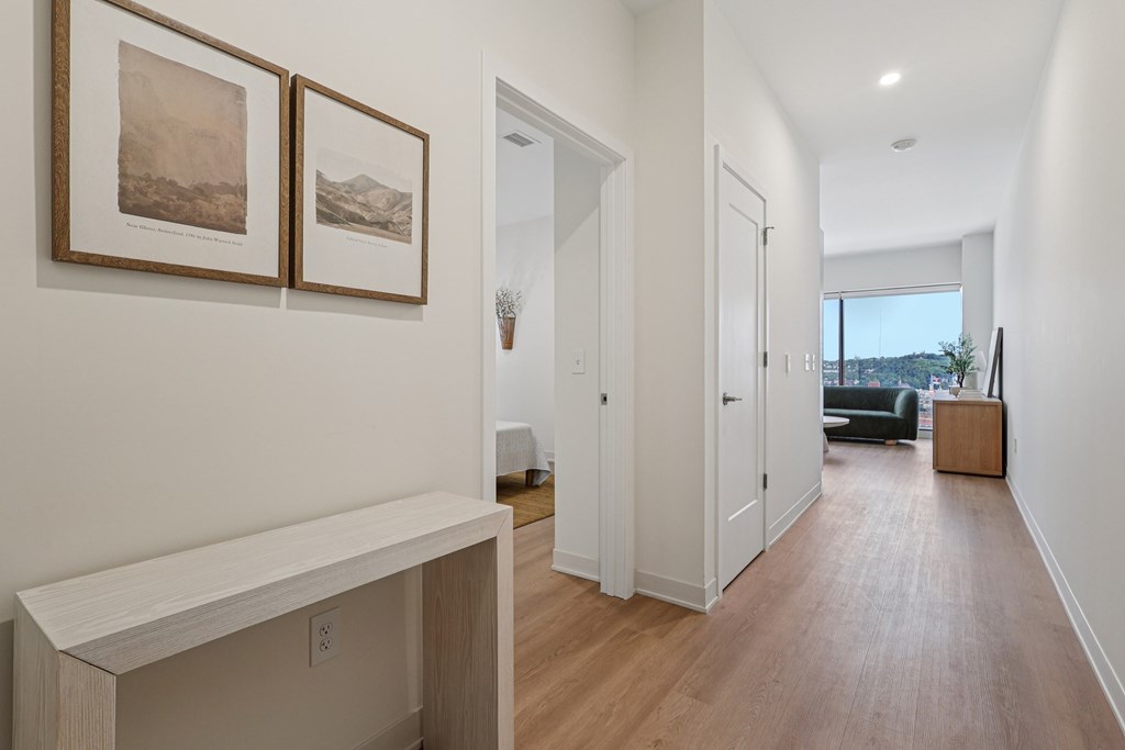 A long hallway with a bench and pictures on the wall.